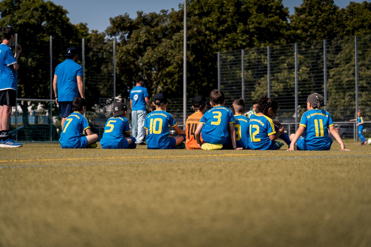 in einer Pause sitzen die jungen Fußballer zusammen auf dem Rasen